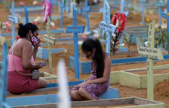 Una mujer y una niña se sientan cerca de las tumbas donde fueron enterradas las personas que fallecieron debido a la enfermedad del coronavirus en Brasil. Foto: REUTERS