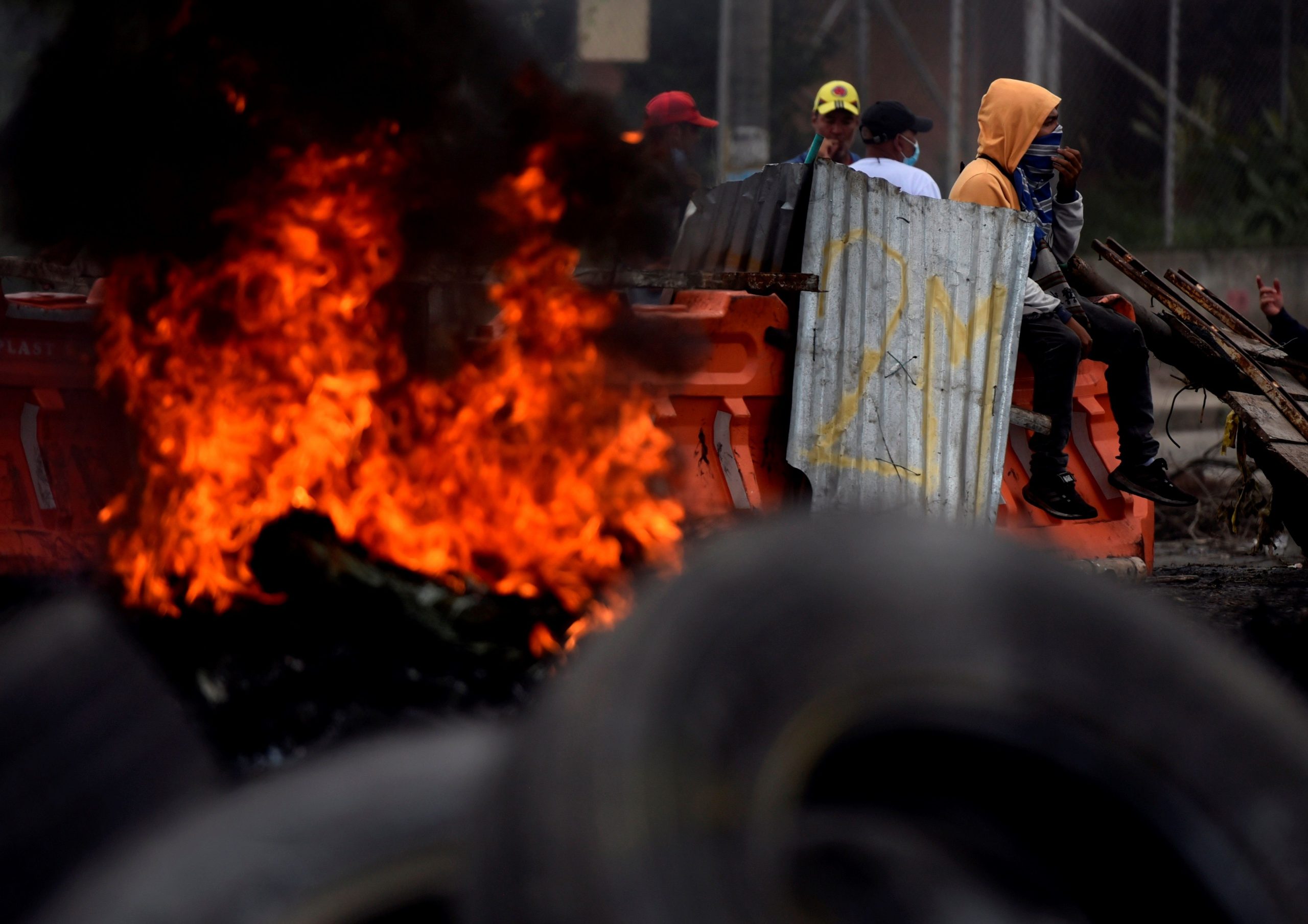 Fotografía del 3 de mayo de 2021 que muestra a un grupo de manifestantes que incendian llantas mientras bloquean vías durante las protestas en Cali (Colombia). Foto: EFE