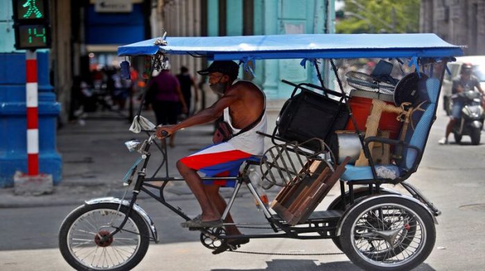 Vida diaria en la Habana, Cuba. Un hombre transporta varios objetos en un bicitaxi. Foto: EFE