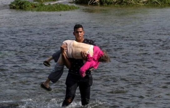 Fotografía de Go Nakamura en el momento en que un joven carga en brazos a una mujer de 65 años de edad para ayudarla a cruzar el río. Foto: REUTERS