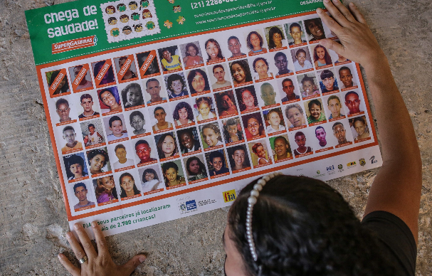Una persona coloca un cartel con decenas de fotos de niños y adolescentes del proyecto SOS Niños Desaparecidos, el 24 mayo de 2021, en una plaza de Río de Janeiro (Brasil). Foto: EFE