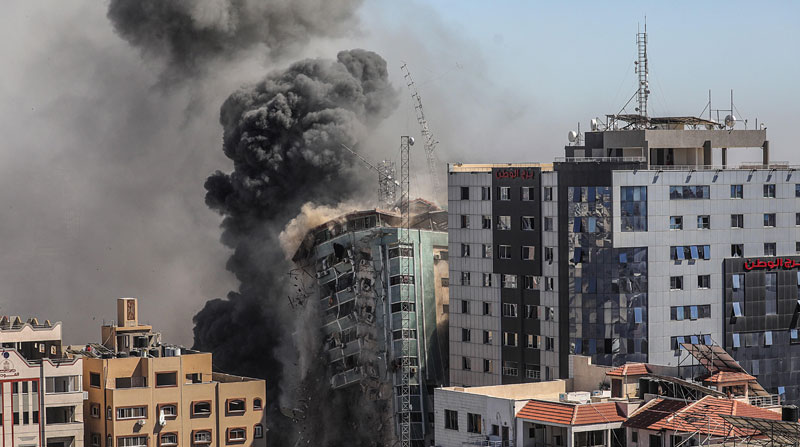 Una columna de humo asciende de un edificio de 14 plantas en la ciudad de Gaza, sede de la agencia de noticias estadounidense AP, la cadena de noticias Al Jazeera y otros medios internacionales, que Israel derribó este sábado 15 de mayo del 2021. Foto: EFE