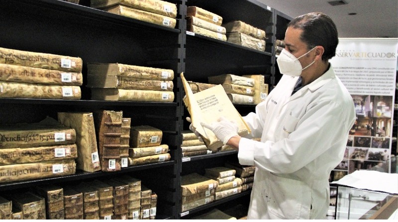 El restaurador Ramiro Endara Martínez sostiene una de las publicaciones que forman parte de la Biblioteca General de la Universidad Central. Cortesía de la fundación Conservartecuador