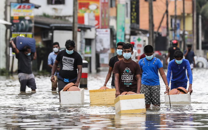 Las víctimas de las inundaciones de Sri Lanka atraviesan una carretera inundada después de las fuertes lluvias en el suburbio de Biyagama en Colombo, Sri Lanka, el 6 de junio de 2021. Foto: EFE