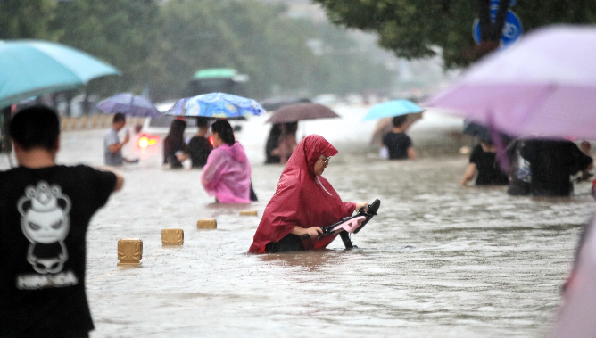 La gente camina por la carretera inundada después de lluvias récord en la ciudad de Zhengzhou, en la provincia de Henan, en el centro de China, el martes 20 de julio de 2021. Foto: EFE