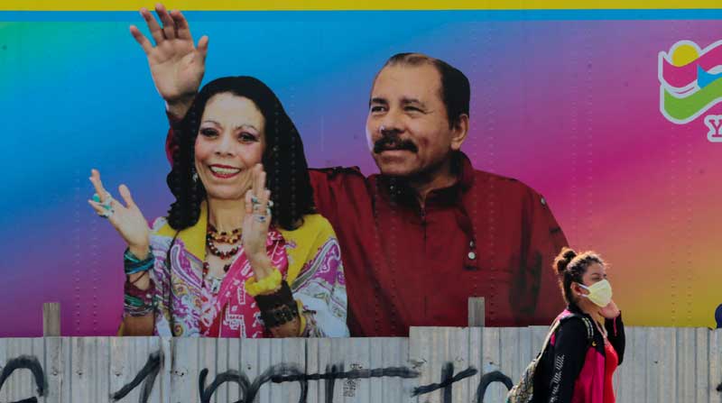 Una mujer con mascarilla camina frente a una foto del presidente de Nicaragua, Daniel Ortega, y la vicepresidenta de Rosario Murillo, en Managua, Nicaragua. Foto: REUTERS