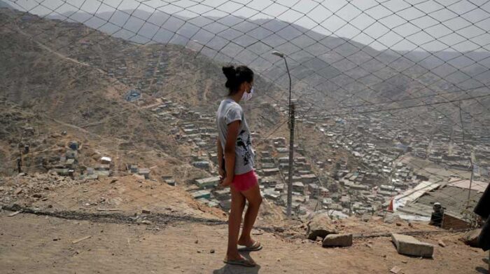 Una joven con tapabocas recorre el asentamiento de Buena Vista, en Lima (Perú). Foto: EFE