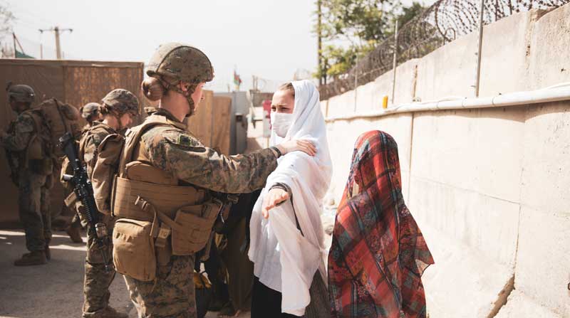 Una infante de marina revisa a dos civiles durante el procesamiento a través de un puesto de control de evacuados (ECC) durante una evacuación en el aeropuerto internacional Hamid Karzai, Kabul, Afganistán, el 18 de agosto de 2021. Foto: EFE