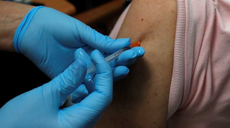 Una enfermera se prepara para inyectar a un hombre una tercera inyección de la vacuna contra el covid-19. Foto: EFE