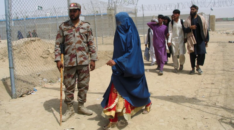 Una mujer con una burqa pasa frente a un soldado paramilitar de Pakistán en un punto fronterizo con Afganistán, en medio de la huida de miles de civiles por la llegada de los talibanes al poder. Foto: Reuters