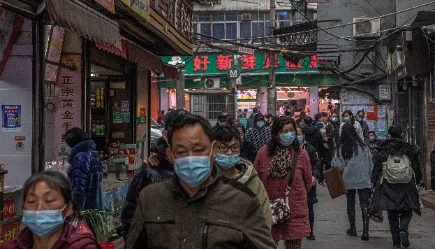 Personas que usan mascarillas protectoras pasan frente a las tiendas en una zona residencial, en Wuhan, China, el 22 de enero de 2021. Foto: EFE