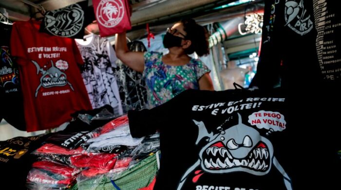 Una mujer vende camisetas con la imagen de tiburones, el 12 de agosto de 2021, en Jaboatao dos Guararapes (Brasil). Foto: EFE