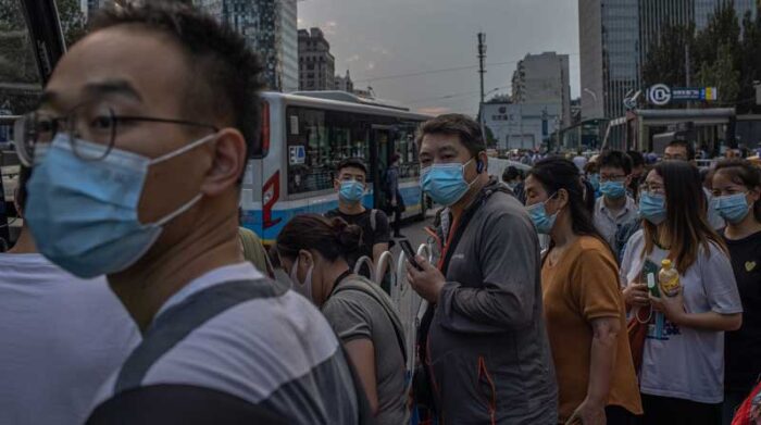 Personas con mascarillas protectoras hacen fila mientras esperan en una estación de autobuses en China. Foto: EFE