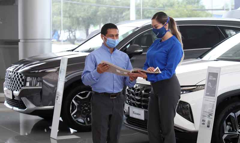 Personal de una concesionaria de vehículos Hyundai, en Quito, muestra el catálogo de un modelo a un cliente. El sector muestra una reactivación. Foto: Julio Estrella / EL COMERCIO