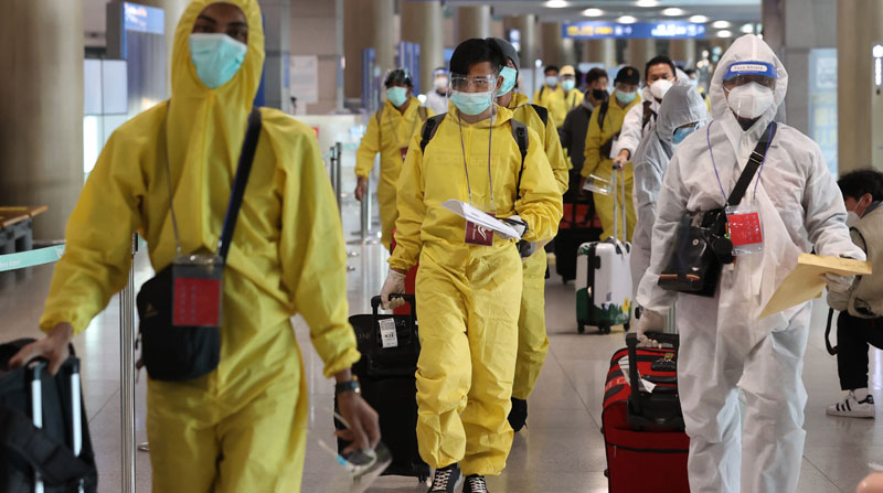 Los pasajeros usan trajes de bioseguridad para abordar los vuelos en Corea del sur, tras la propagación de la variante ómicron. Foto: EFE