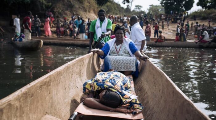 República Centroafricana, enero de 2021. La comadrona Odette acompaña a Amatou (acostada en la piragua), que está embarazada y a punto de dar a luz, al otro lado del río para ser trasladada al hospital apoyado por MSF en Bangassou. Foto: Alexis Huguet 