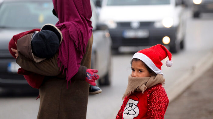Una niña romaní, vestida con un disfraz de Papá Noel, suplica al borde de la carretera esperando donaciones de los transeúntes en la víspera de Año Nuevo, en Pristina, Kosovo, el 31 de diciembre de 2021. Foto: EFE
