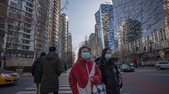 Personas con mascarillas protectoras cruzan una calle en el distrito comercial de Beijing, China, el 13 de diciembre de 2021. Foto: EFE