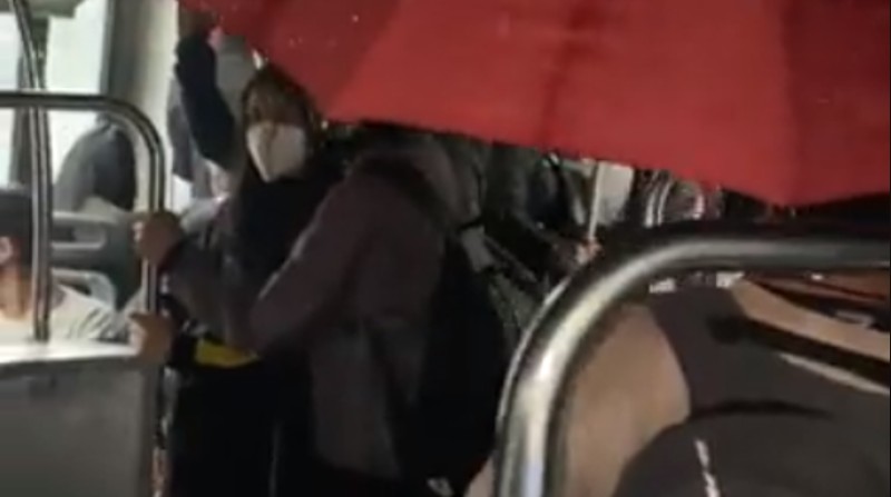 En un video se ve a una persona que viaja dentro de uno de los buses articulados del sistema Ecovía, con un paraguas rojo abierto. Foto: Captura