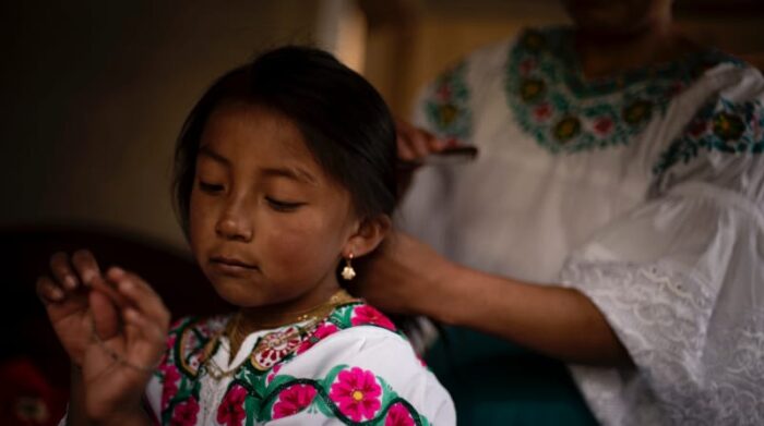 La madre de Sayana Cuasque la peina para que pueda ir a la escuela. El uniforme es el traje tradicional. Foto: Johis Alarcón