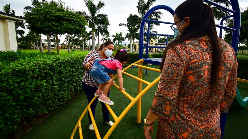 María (der.) observa a su esposa Denisse y a su hija Raphaella, mientras juegan en el parque de su conjunto, ubicado en Guayaquil. Foto: Enrique Pesantes / EL COMERCIO