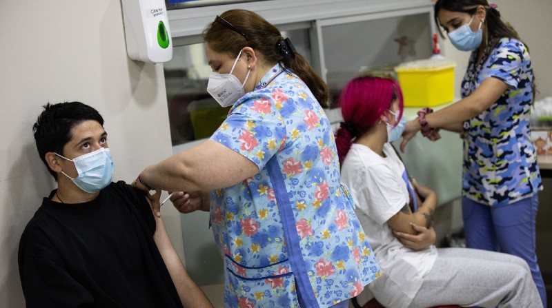 Dos personas reciben una dosis de la vacuna contra la covid-19, hoy, en un centro de vacunación de Santiago (Chile). Foto: EFE