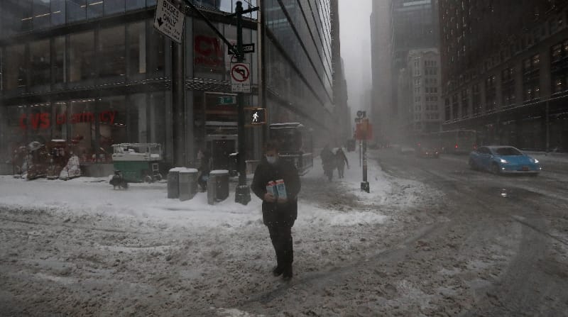 Un hombre lleva contenedores de leche por la Octava Avenida en Nueva York, Estados Unidos, este 29 de enero de 2022, durante una tormenta de nieve, de nominada ciclón bomba. Foto: EFE