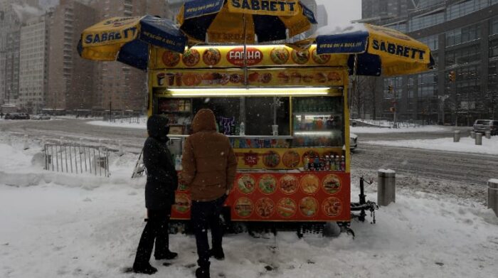 La gente se detiene para comer en un puesto ambulante en Columbus Circle en Nueva York, EE.UU. este 29 de enero de 2022. Foto: EFE