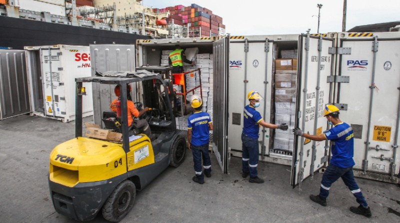 Cuatro estibadores de Terminal Portuario de Guayaquil preparan el embarque de 10 conte­nedores. Foto: Enrique Pesantes / El Comercio