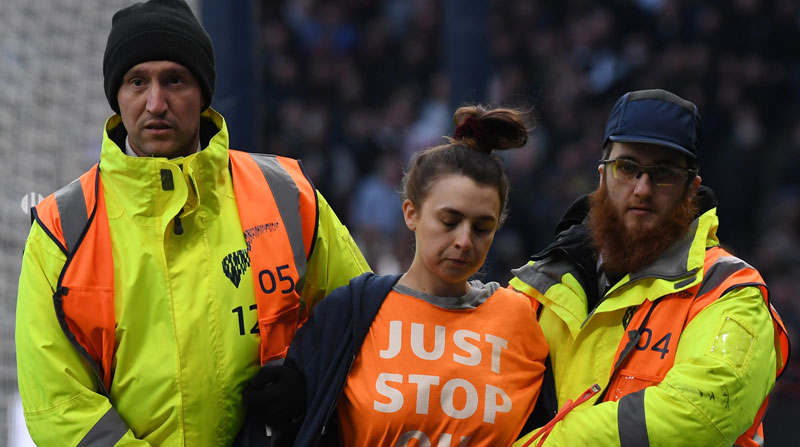 Integrantes de la seguridad del estadio del Tottenham Hotspur retiran a una aficionada que ingresó a la cancha. Foto: EFE