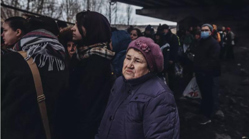 Una mujer mayor, junto a otras personas, espera para cruzar el río de Irpin. Foto: Europa Press