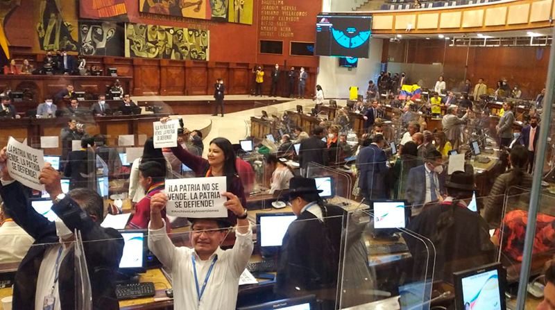 Asambleístas de Unes y Pachakutik sostienen carteles con insignias como “la Patria no se vende” y “el país o la banca”. Foto: EL COMERCIO