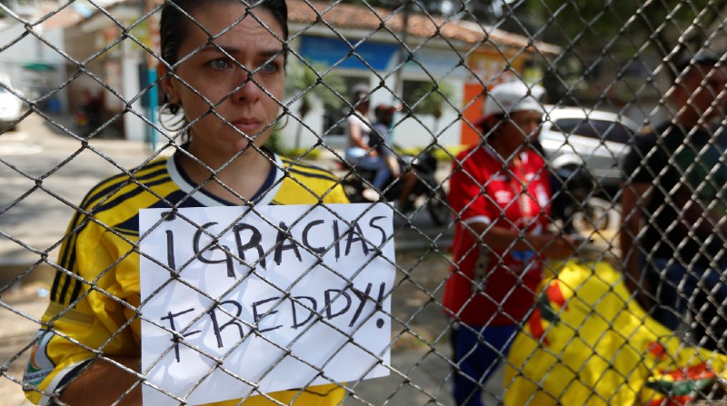 Una aficionada del ex futbolista colombiano Fredy Rincón sostiene un cartel en el exterior de medicina legal, donde se encuentra el cuerpo de Rincón de 55 años, en Cali (Colombia). Foto: EFE