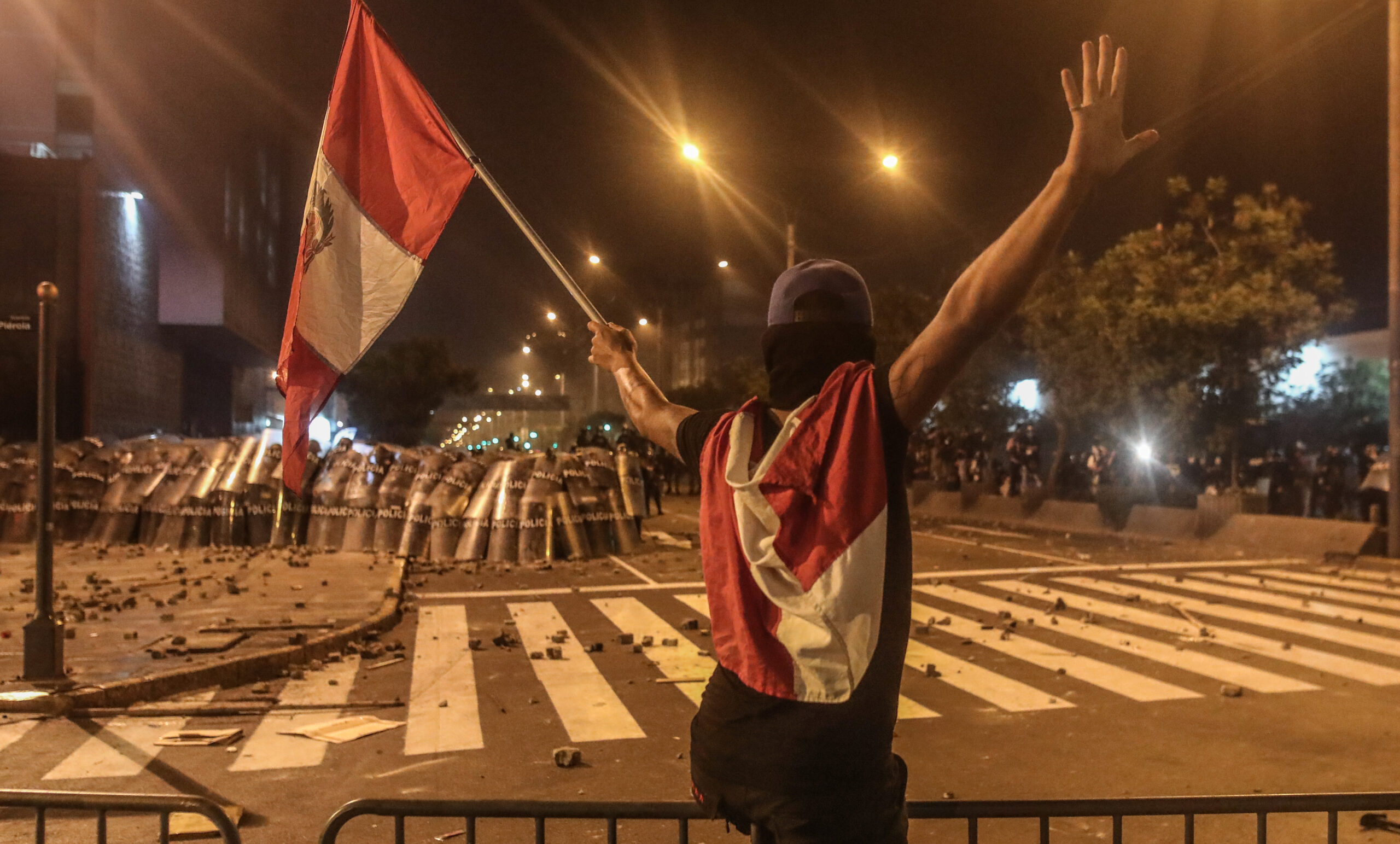 Un manifestante ondea una bandera frente a un cerco policial el 6 de abril del 2022, en Lima (Perú). Foto: EFE