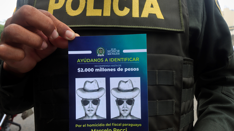 Un policía muestra el volante que identifica al presunto autor material del asesinato del fiscal antimafia paraguayo Marcelo Pecci. Foto: EFE