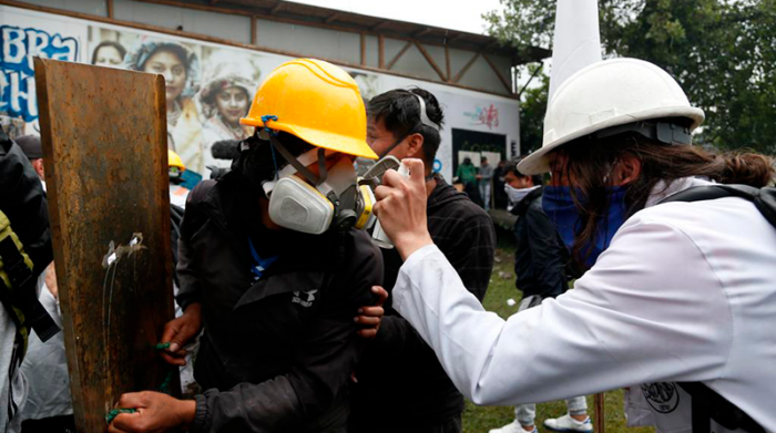 Un manifestante es ayudado por un paramédico para repeler los efectos del gas lacrimógeno en sus ojos. Foto: EL COMERCIO