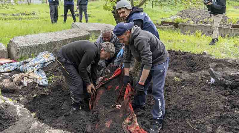 Expertos policiales exhumaban el cuerpo de un civil hallado en el jardín de una vivienda en el área de Járkov, Ucrania. Foto: EFE.