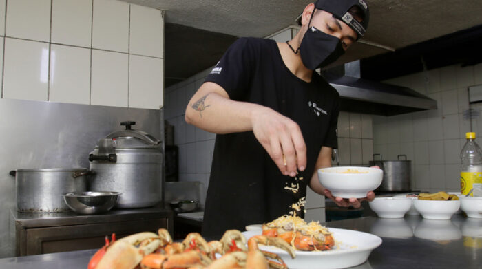El chef añadiendo toques de queso a los carapachos rellenos de pulpa de cangrejo para gratinarlos posteriormente. Foto: Carlos Noriega Y Diego Pallero / EL COMERCIO