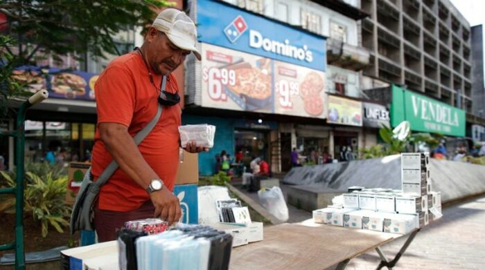 Un hombre vende tapabocas en un puesto instalado en la Avenida Central, en Ciudad de Panamá (Panamá). Foto: EFE