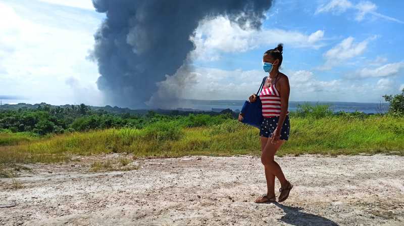 Una mujer frente a la columna de humo generada por el incendio en un depósito de combustible hoy, en Matanzas (Cuba). Foto: EFE/ Ernesto Mastrascusa