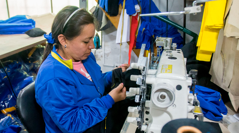 Una mujer trabaja en la confección de un uniforme escolar en uno de los talleres del Centro de la ciudad de Quito. Foto: Carlos Noriega / EL COMERCIO