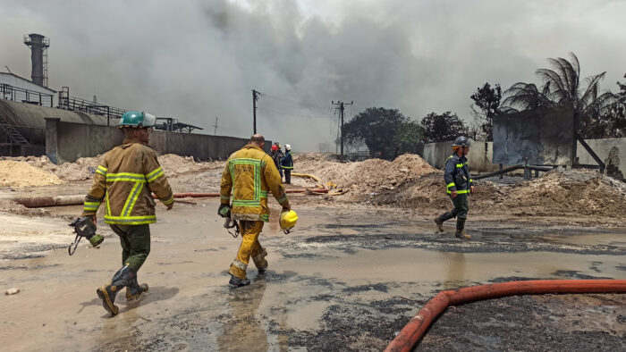 Bomberos trabajan hoy, en las labores de extinción de un incendio tras la explosión en la base de contenedores en la zona industrial de la bahía de Matanzas (Cuba). Foto: EFE.
