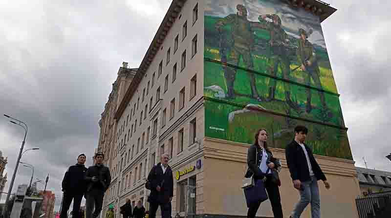 Ciudadanos rusos caminan cerca de un edificio de apartamentos en uno de cuyos costados se pintó un mural de apoyo a las acciones militares en Ucrania. Foto: EFE