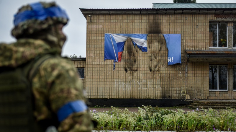 Un soldado de Ucrania observa una pancarta prorrusa quemada en una de las zonas donde las tropas de Moscú han cedido terreno. Foto: EFE.