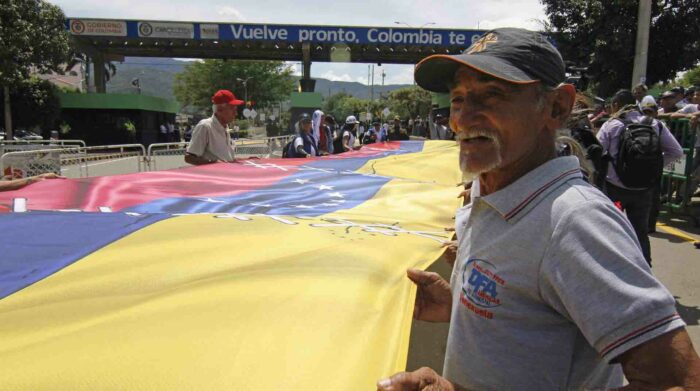 Un grupo de personas sostiene una bandera en el puente Simón Bolívar durante un acto de reapertura de la frontera entre Colombia y Venezuela, en Cúcuta. Foto: EFE