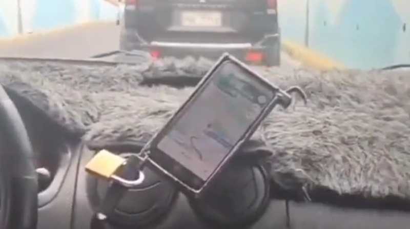 Taxista asegura su celular con un candado. Foto: Captura de video Twitter @MinMedio