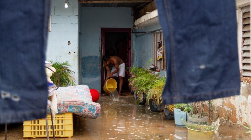 Un hombre saca agua de su casa inundada por las lluvias, en una fotografía de archivo. Foto: EFE