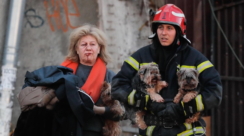 Un rescatista ucraniano ayuda a una mujer herida y a sus perros tras un bombardeo en el centro de Kiev. Foto: EFE