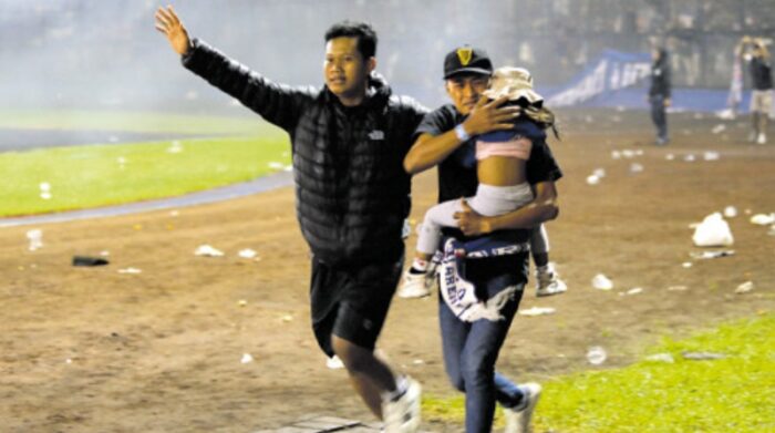 Una niña es evacuada durante choques entre aficionados en el Estadio Kanjuruhan, en la ciudad de Malang. Foto: EFE.