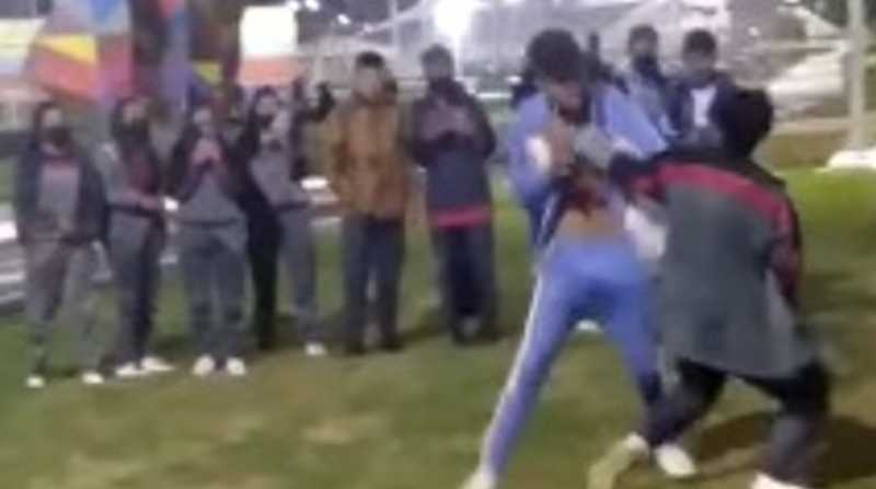 Dos adolescentes con diferente color de uniformes pelean en un parque. Foto: Captura de video